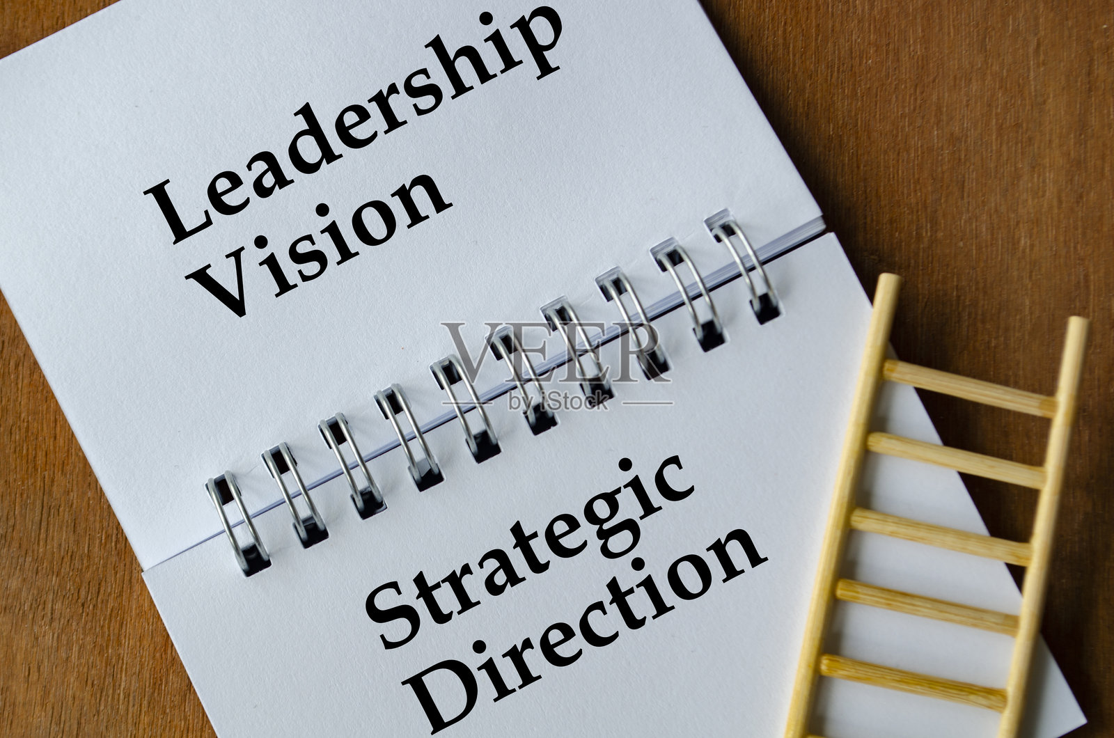 笔记本上写着“领导愿景与战略方向”，旁边有一个小梯子靠在页面上。照片摄影图片