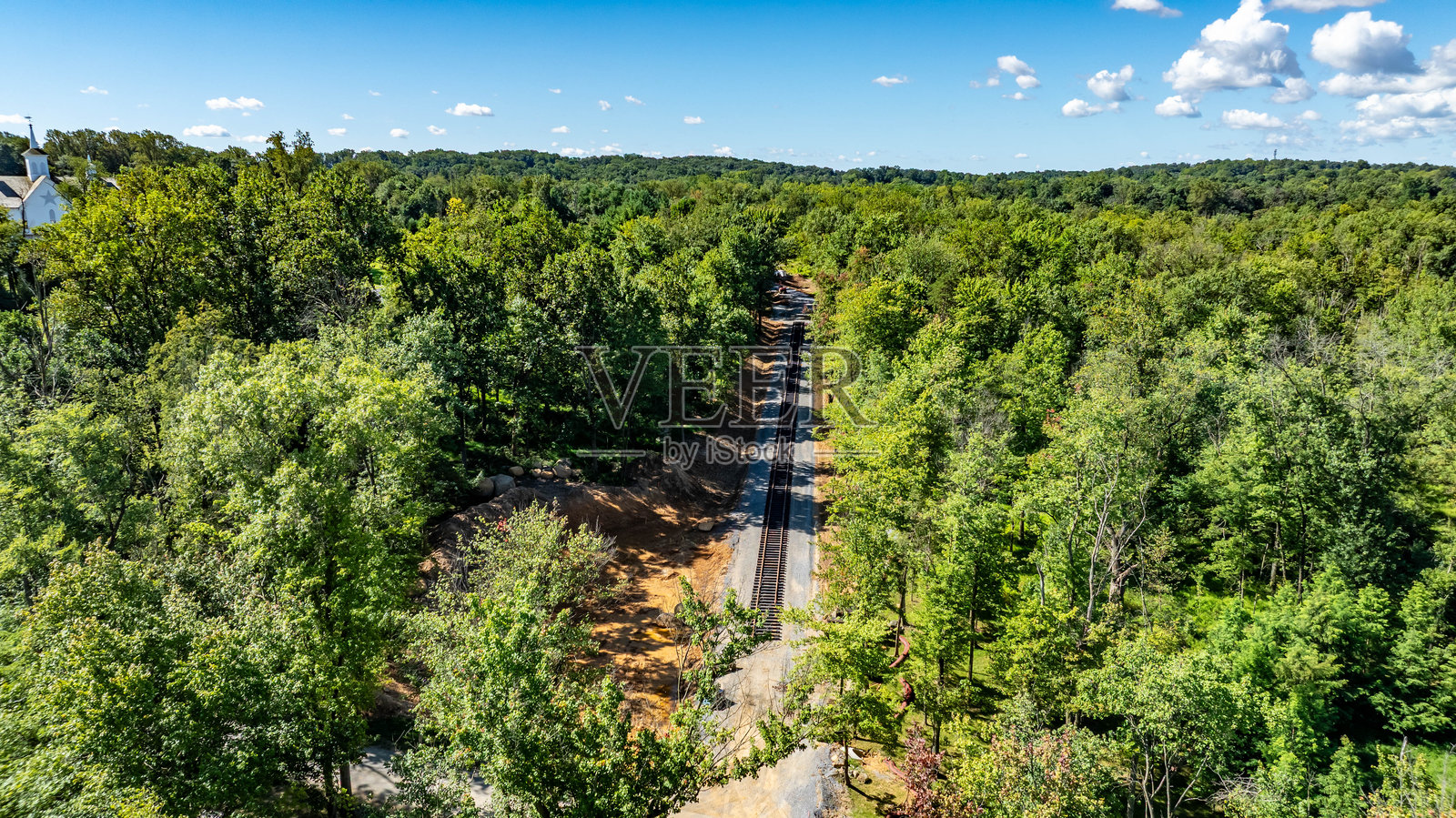 铁路轨道穿过宁静森林中的郁郁葱葱的绿意照片摄影图片