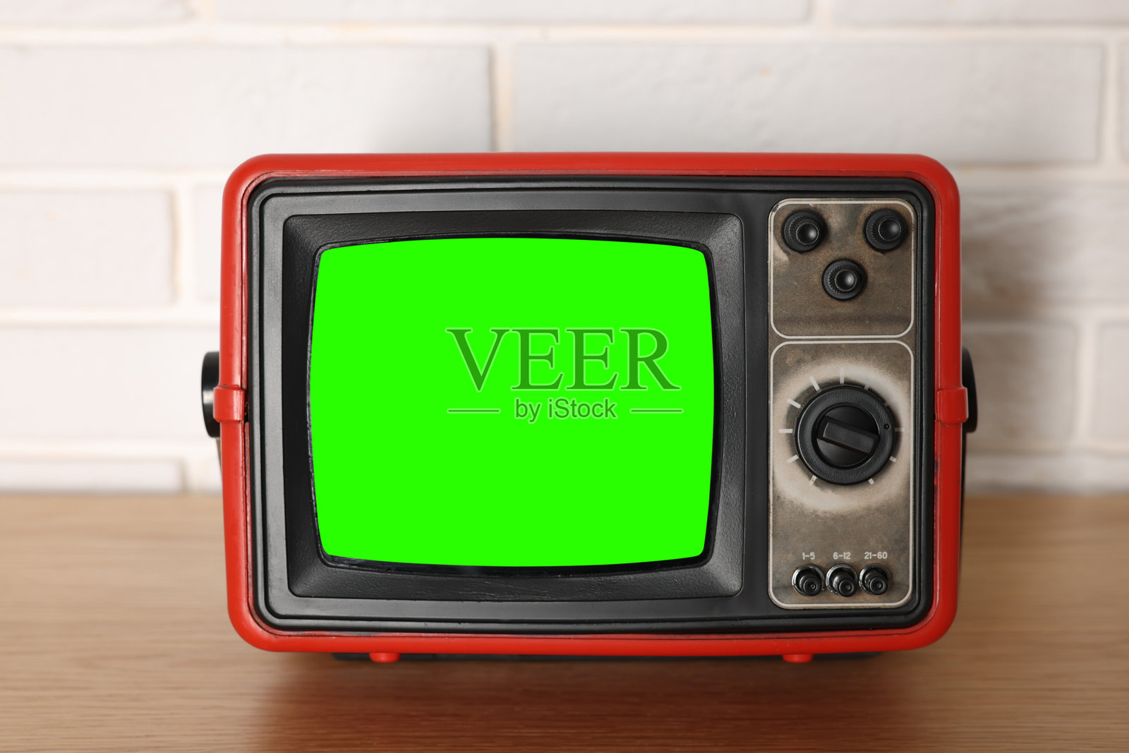 复古电视机放在木桌上，旁边是白色砖墙，绿色屏幕。色度键。照片摄影图片