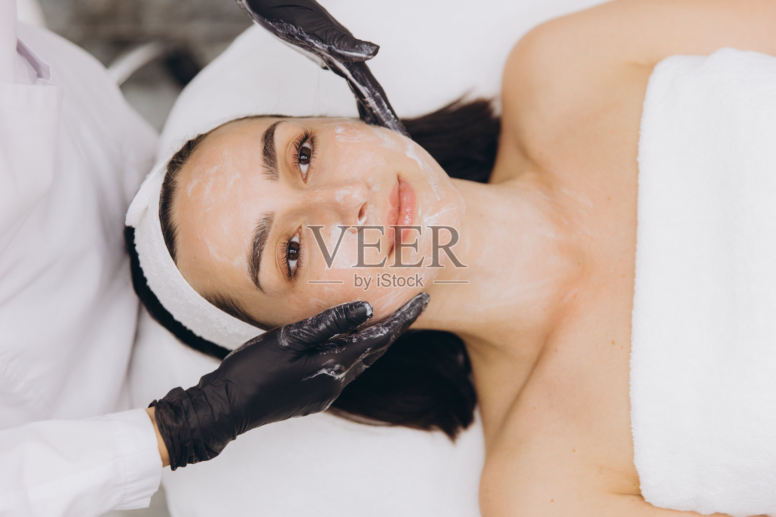 美容师为躺在床上的年轻女性敷面膜照片摄影图片