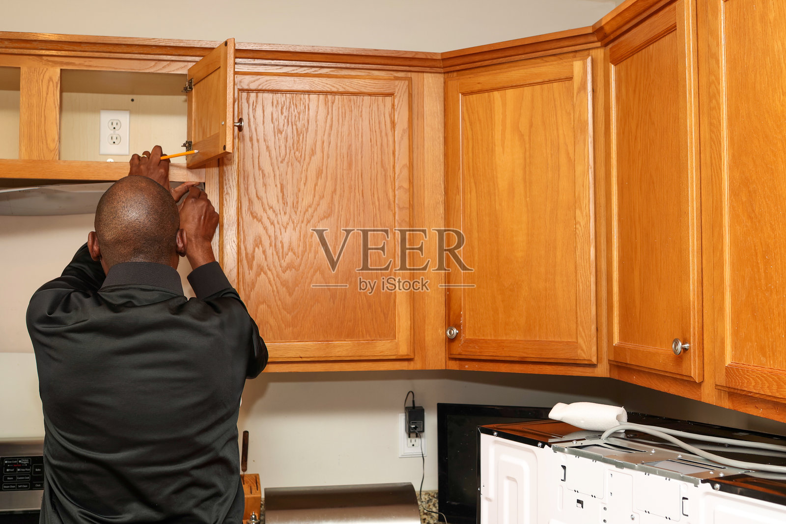 一位黑人男性正在安装新的微波炉照片摄影图片