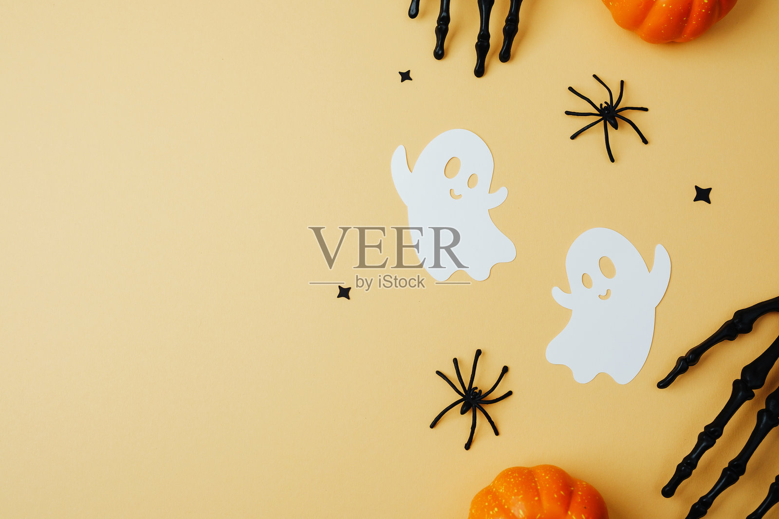 万圣节的鬼魂、蜘蛛、骷髅手和南瓜排列在柔和的背景上。照片摄影图片