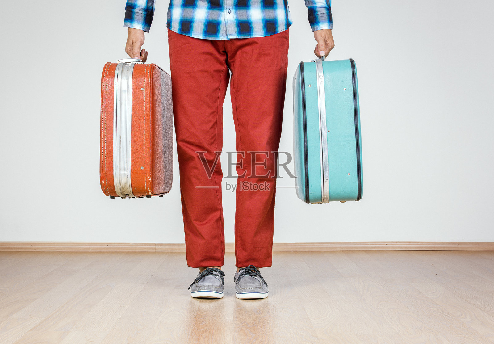 男人手持两个色彩斑斓的复古行李箱，低角度拍摄照片摄影图片