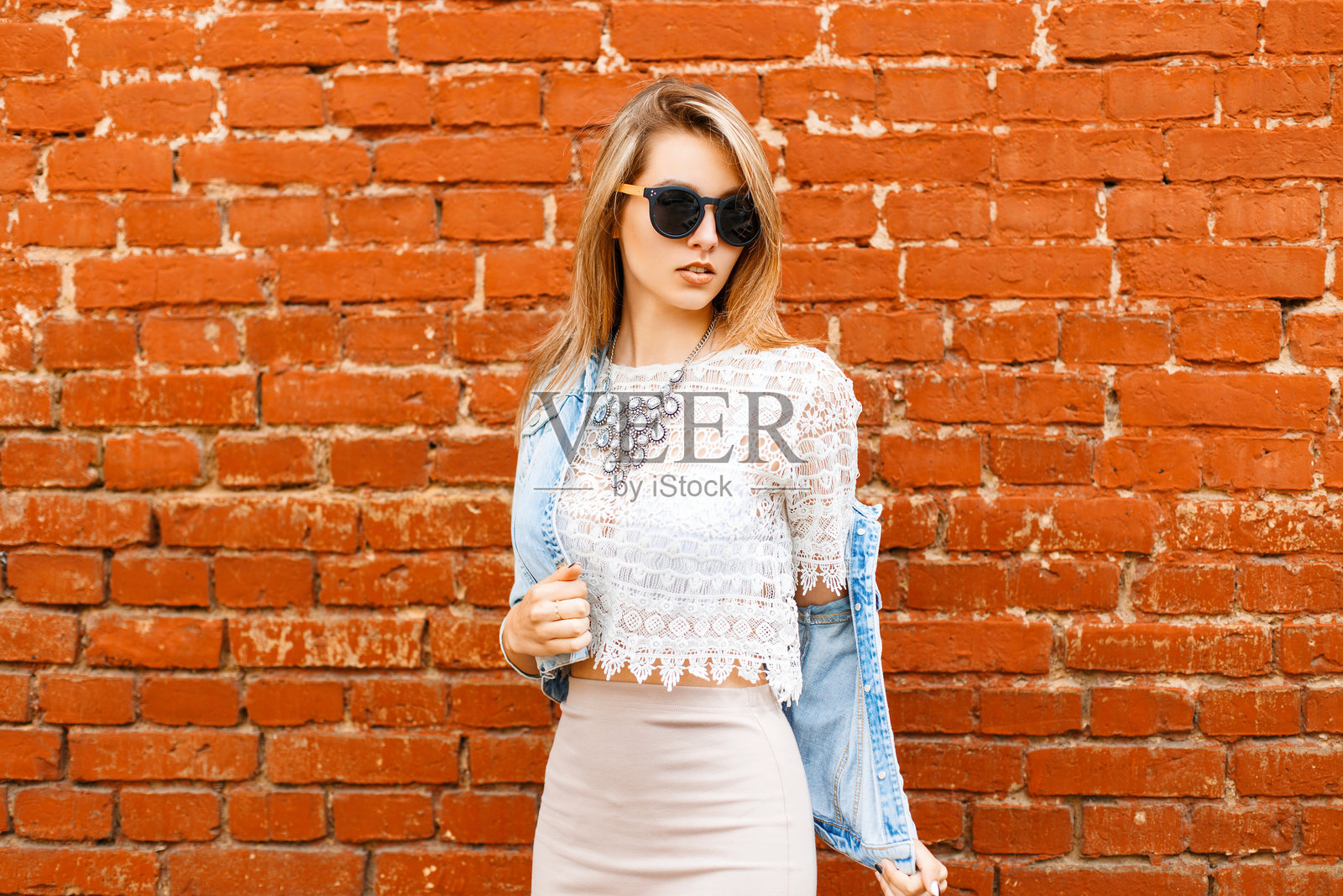 美丽的女孩穿着复古蕾丝衬衫和太阳镜，正在脱下她的外套。照片摄影图片