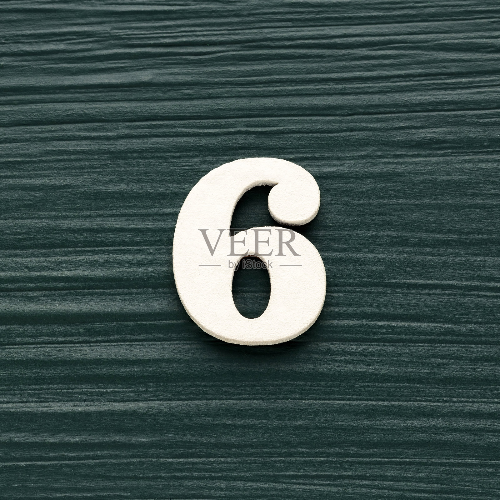 第六号白色棋子置于质朴的深绿色背景上照片摄影图片