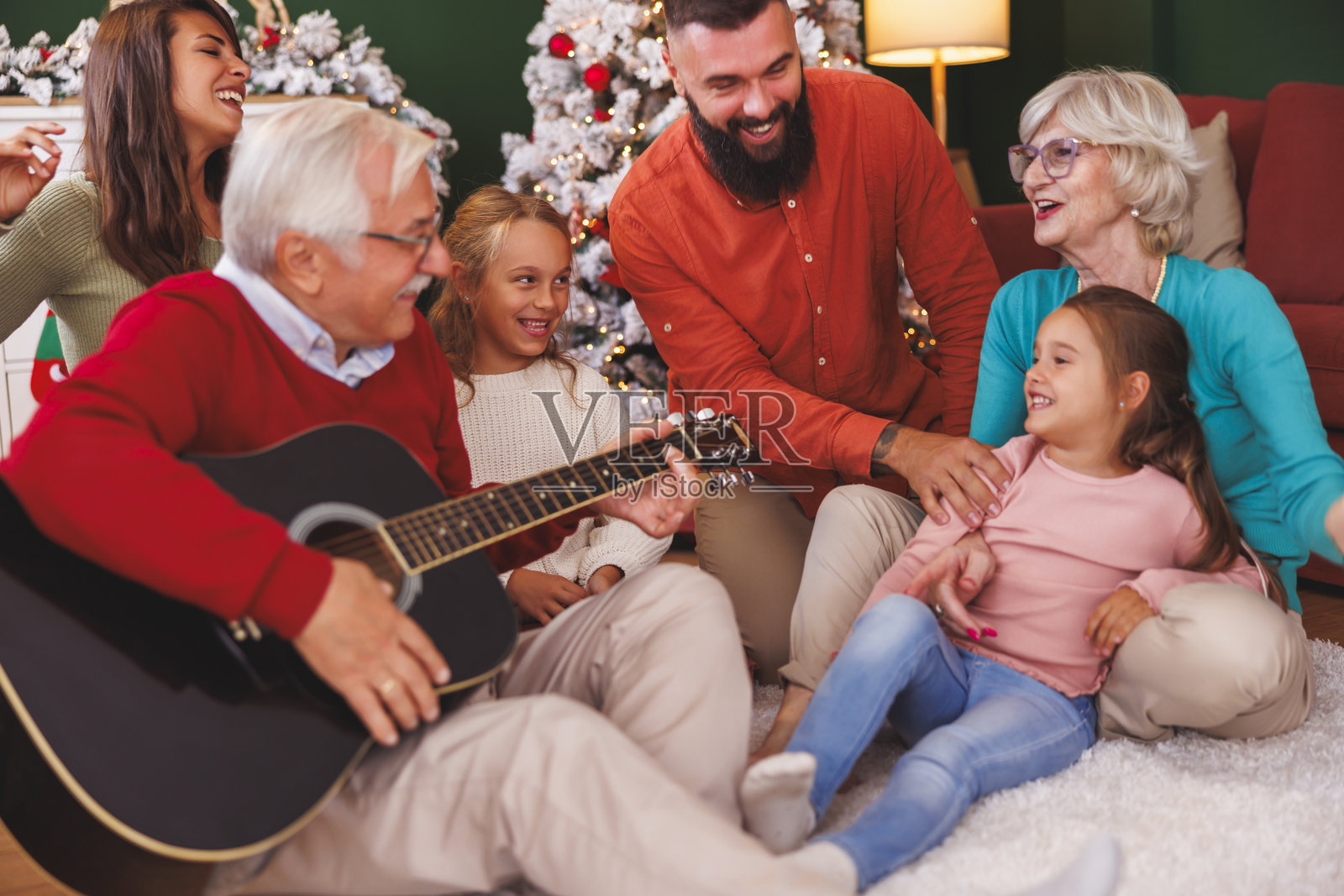 多代家庭在庆祝圣诞节时弹吉他唱圣诞歌曲照片摄影图片