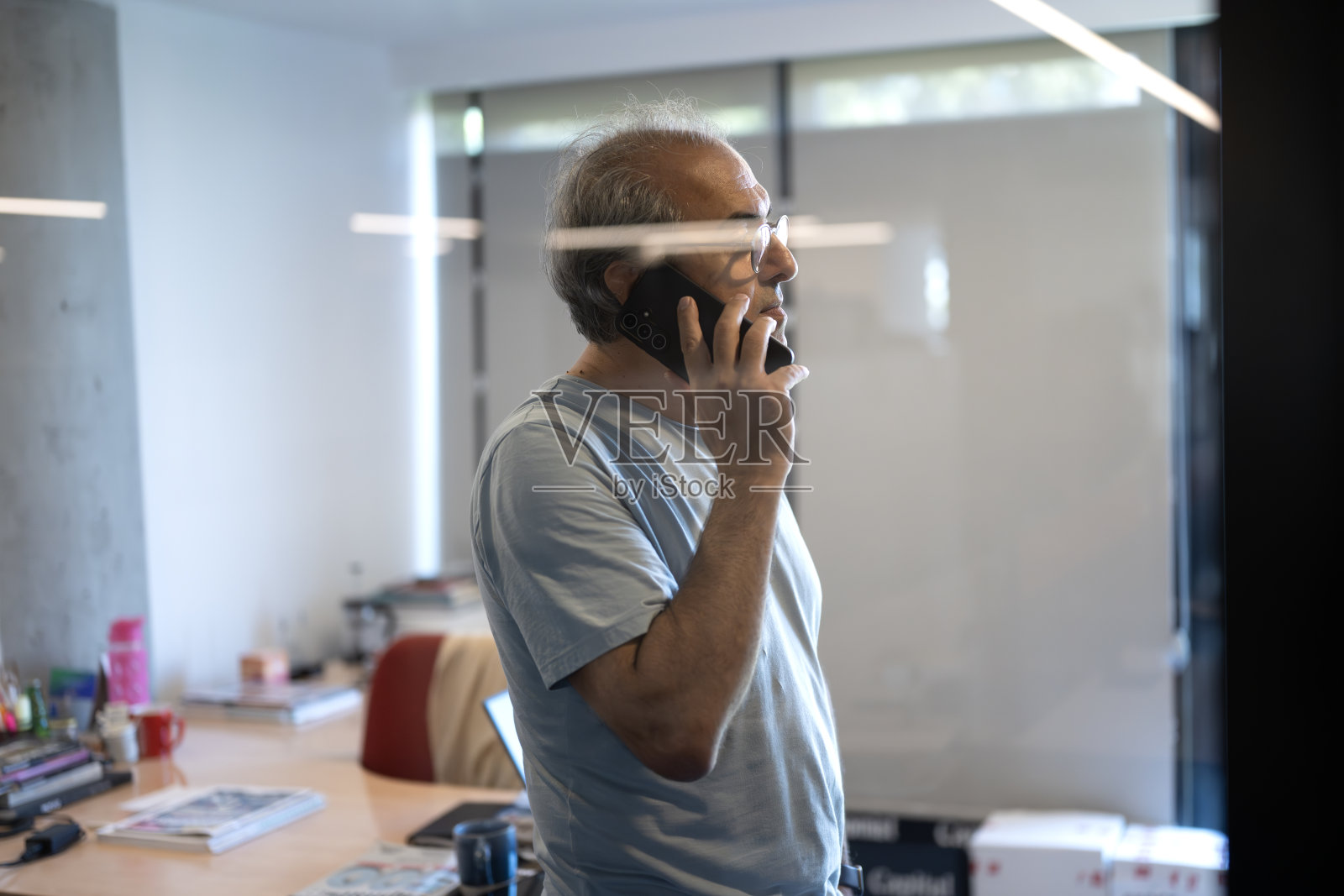 微笑的成熟男士在办公室使用现代智能手机照片摄影图片