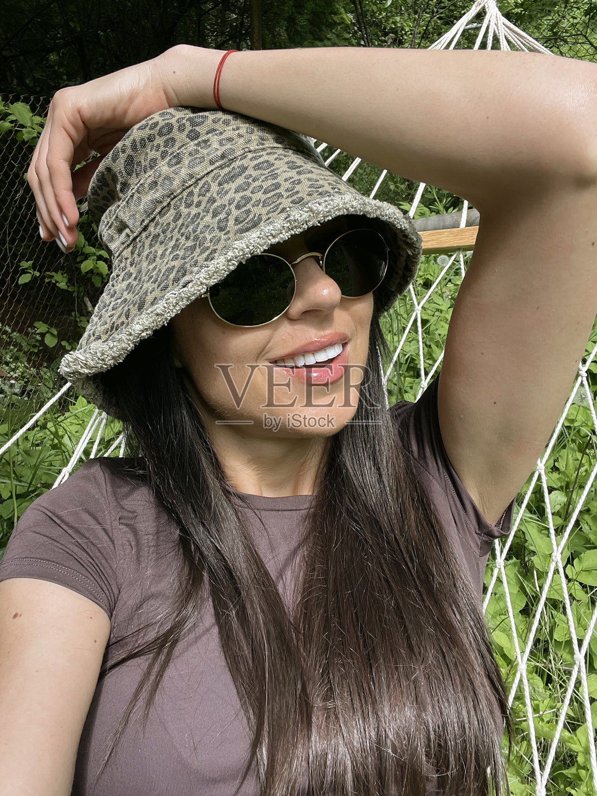 戴着帽子和太阳镜的女人在吊床上放松照片摄影图片