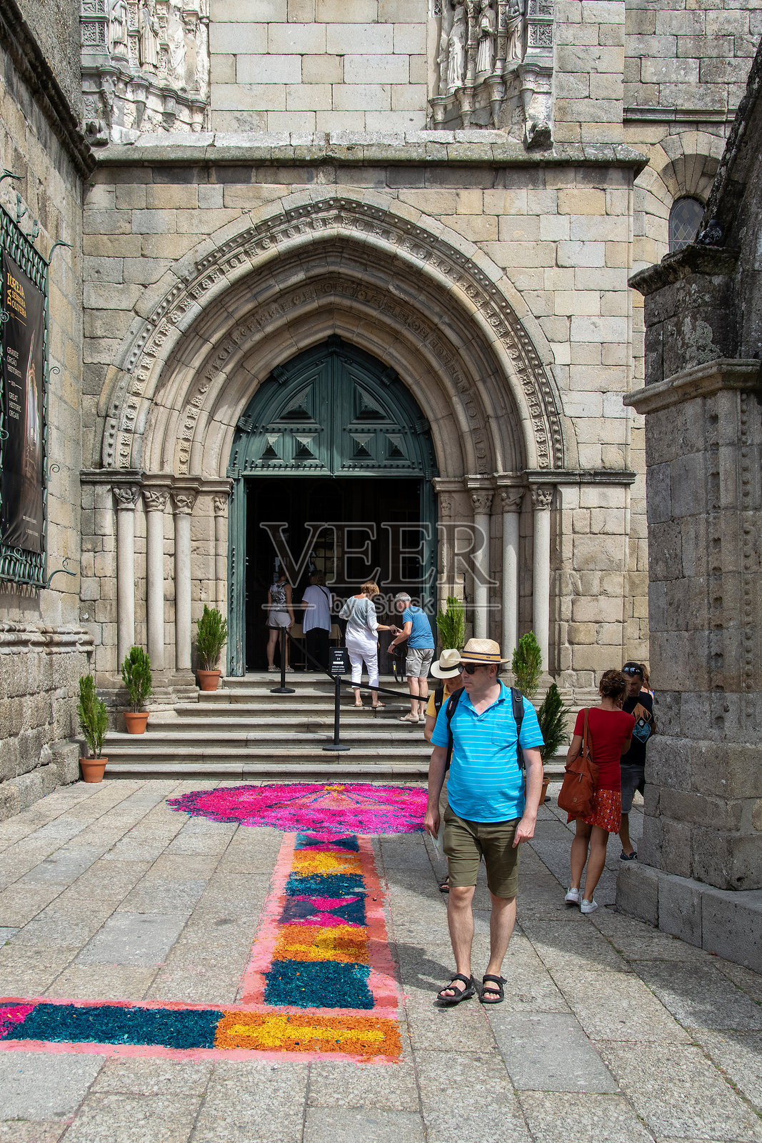 人们走进葡萄牙吉马良斯市的教堂,地毯色彩斑斓。照片摄影图片