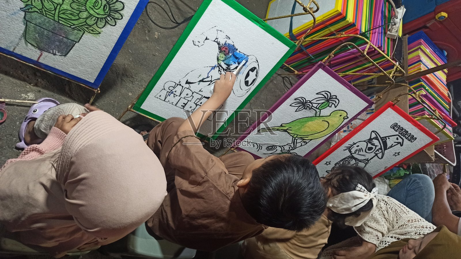 孩子在夜市的软木画布上绘画照片摄影图片