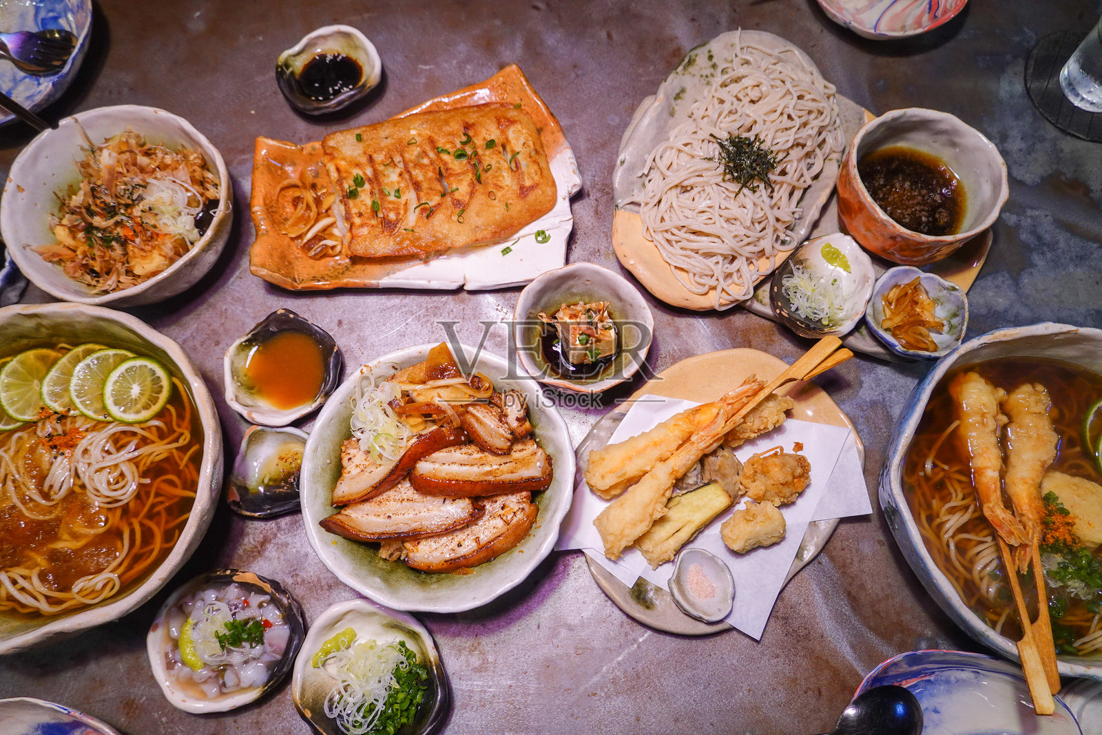 餐厅桌上的美味日本料理多样选择。虾天妇罗、饺子、米饭和拉面。照片摄影图片