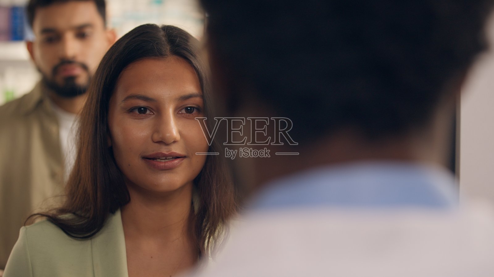 印度女性顾客在药店购买药物，药剂师为她提供专业的健康咨询和药物推荐。照片摄影图片