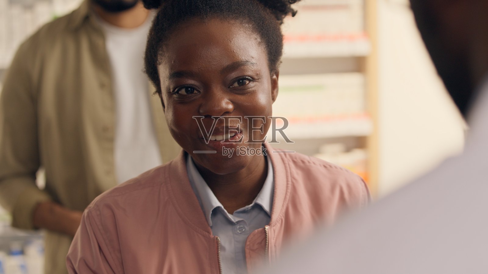 在药店购买药品的顾客，非洲女性微笑着，药剂师男性协助客户购买药物，在药店收银台办理药品订单。照片摄影图片