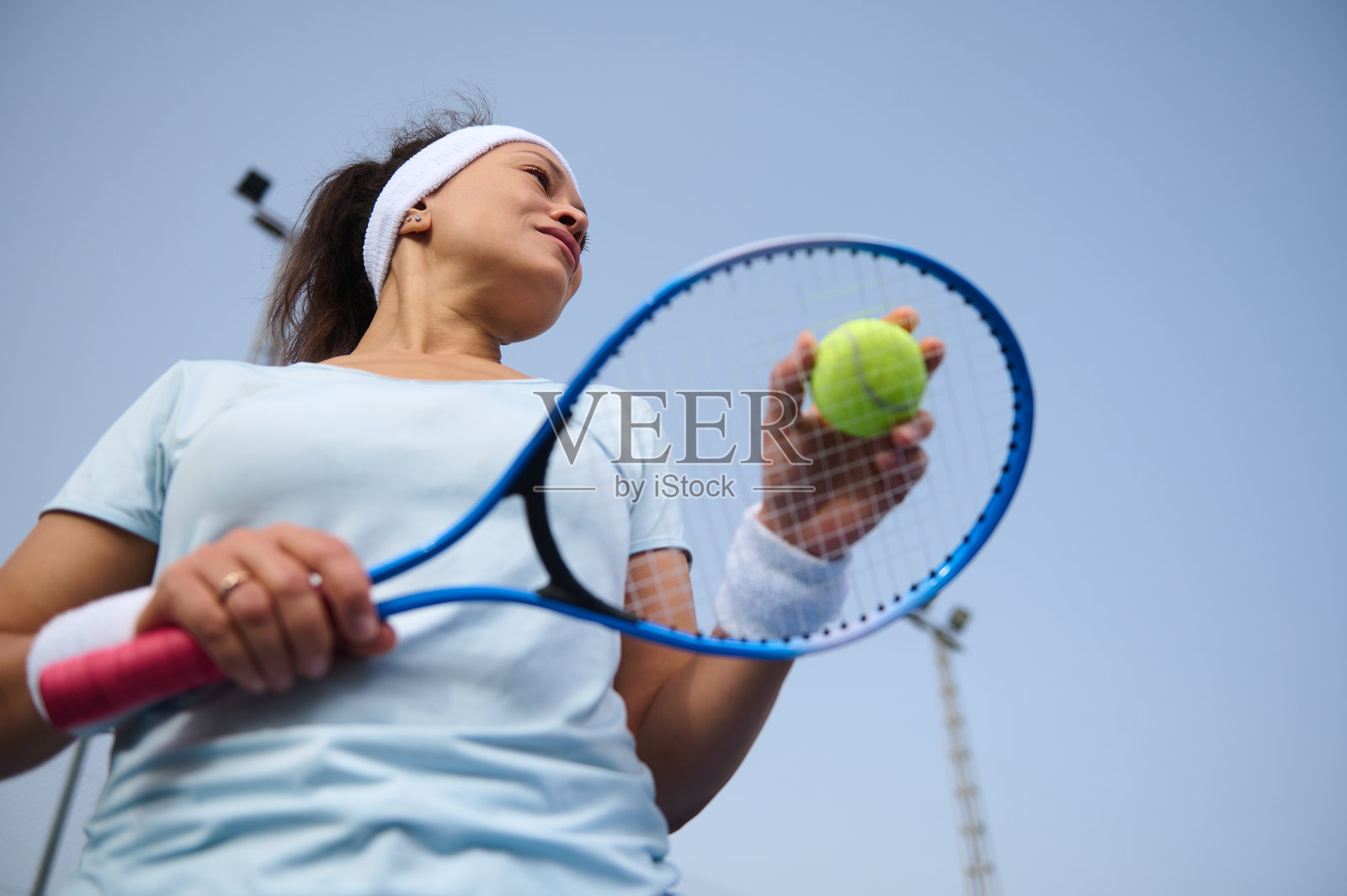 专注的网球运动员手持球拍和网球，背景为蓝天照片摄影图片