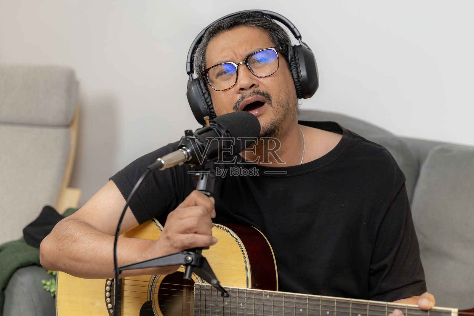 年轻男子在家工作室里弹吉他并录制播客照片摄影图片