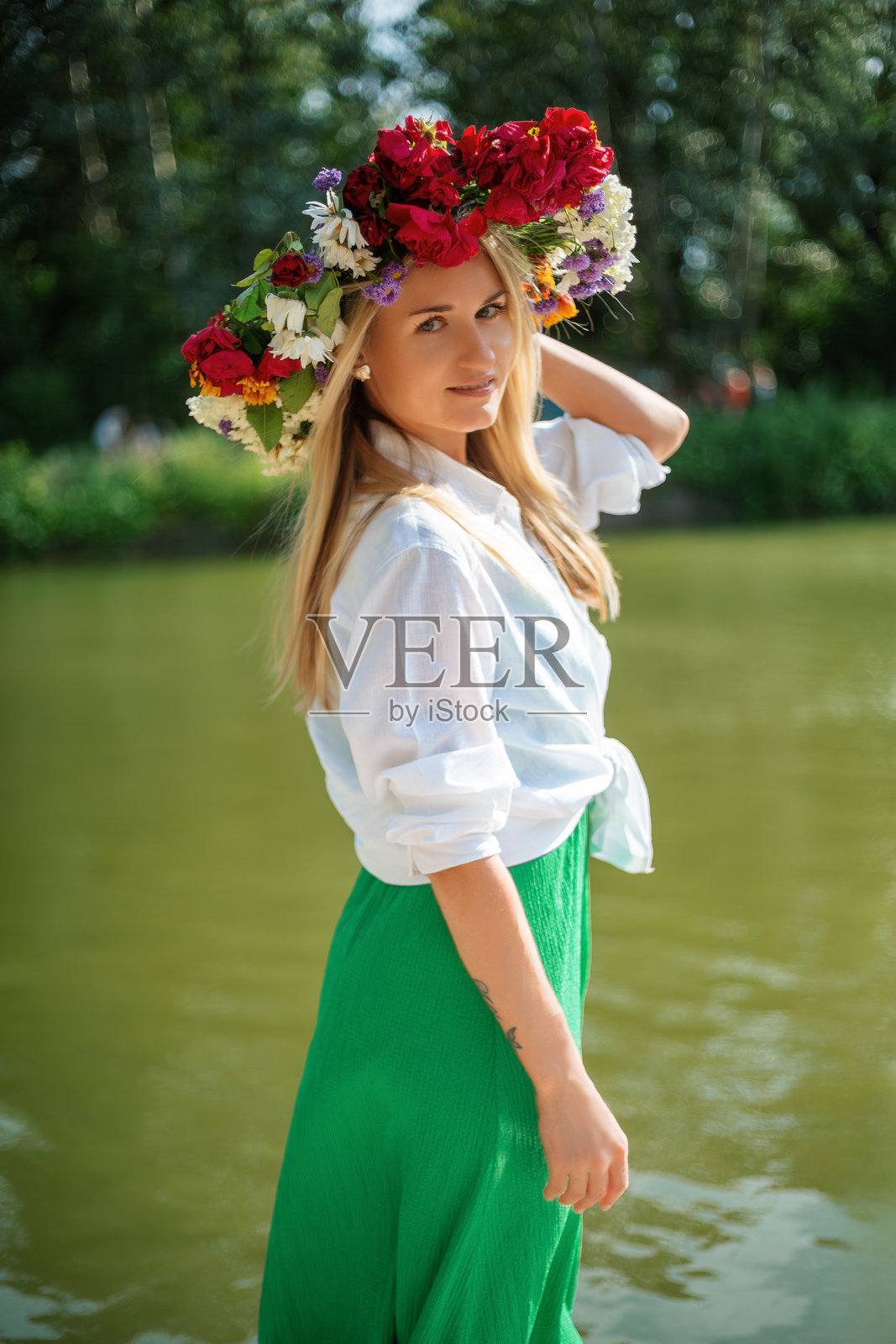年轻的金发女子戴着花冠，在河边摆姿势照片摄影图片