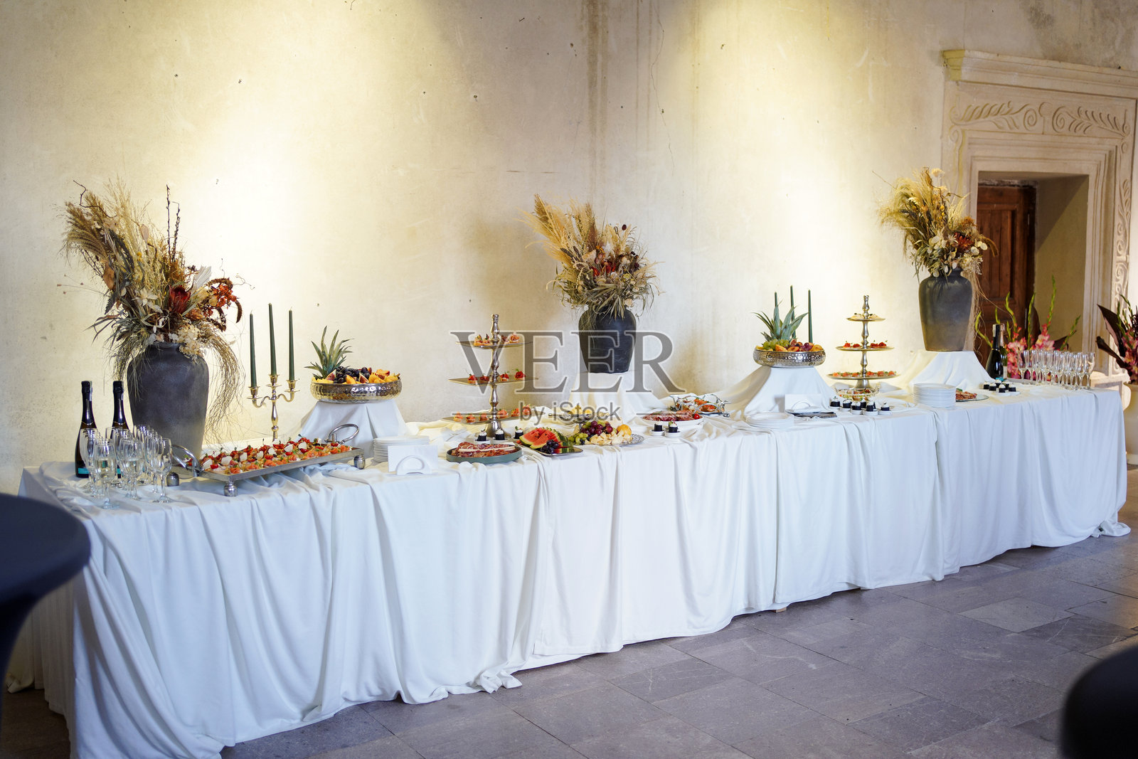 长长的装饰自助餐桌，上面摆满了饮料、水果、开胃菜和鲜花，适合庆祝活动。照片摄影图片