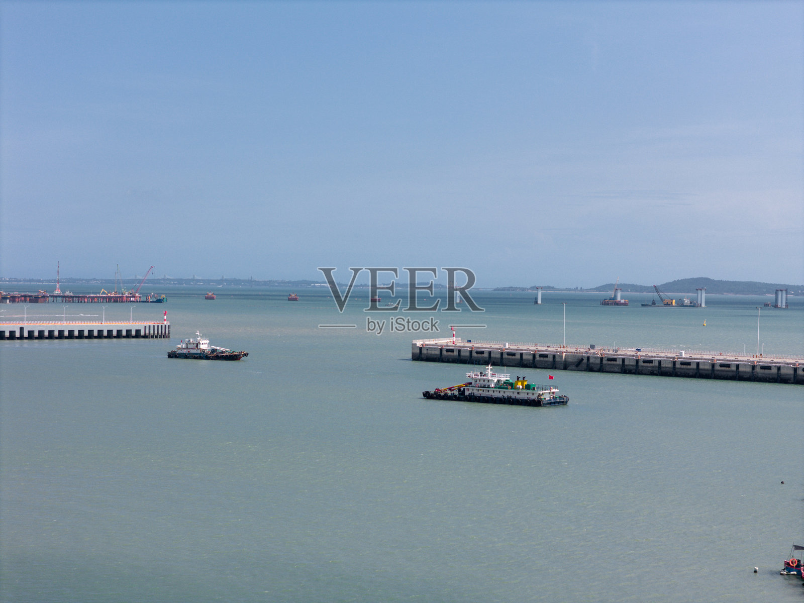 港口的鸟瞰图，拖船在码头和泊位附近作业，天空晴朗。照片摄影图片