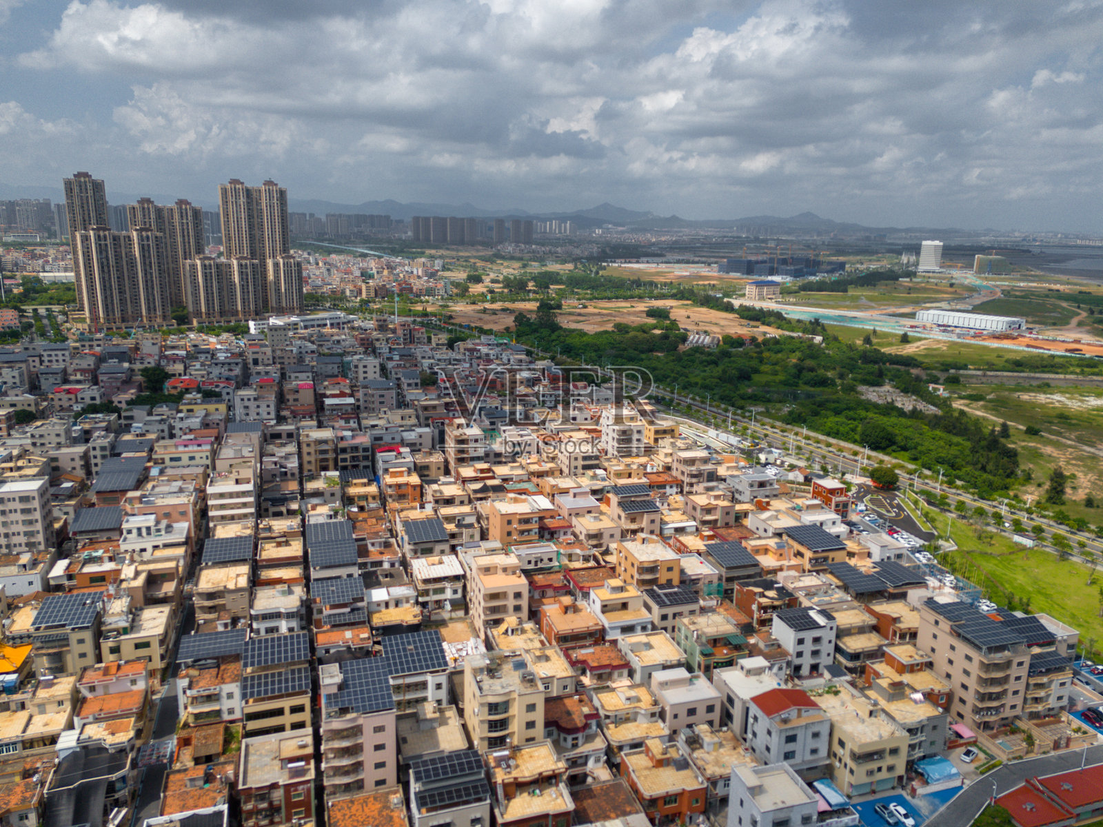 城市边缘密集住宅区的鸟瞰图，背景中有太阳能电池板和现代高层建筑照片摄影图片