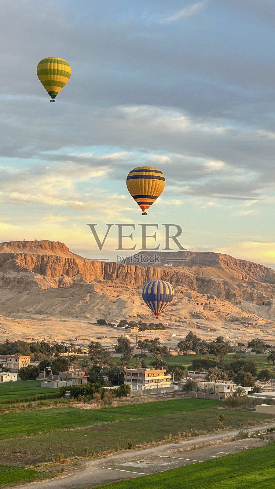 日出时分,热气球在卢克索上空飞翔,背景是沙漠山脉。照片摄影图片