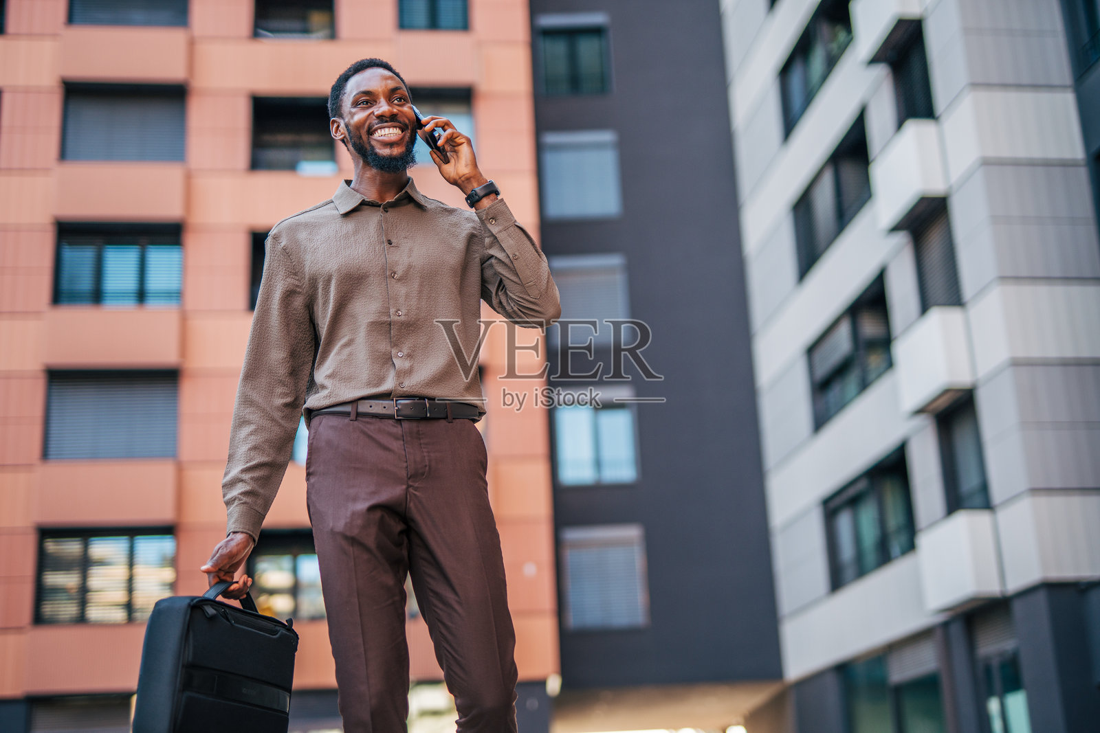 微笑的商人在城市中走路并打电话照片摄影图片