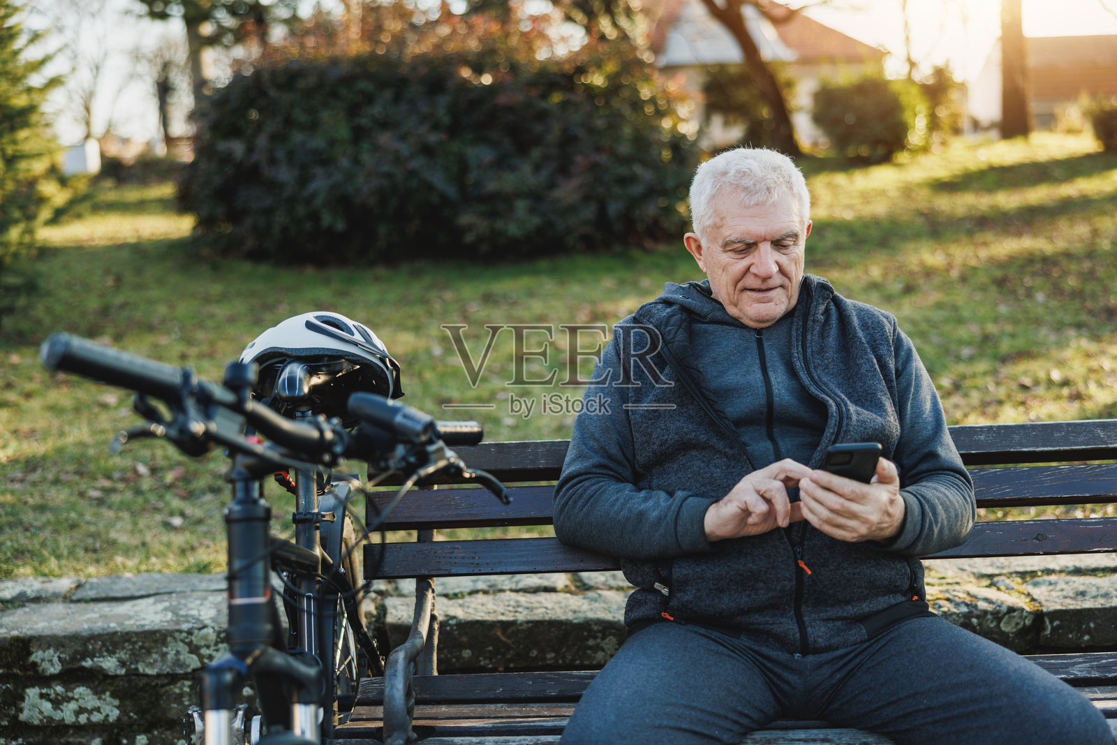 公园里坐在长椅上使用手机的男人照片摄影图片