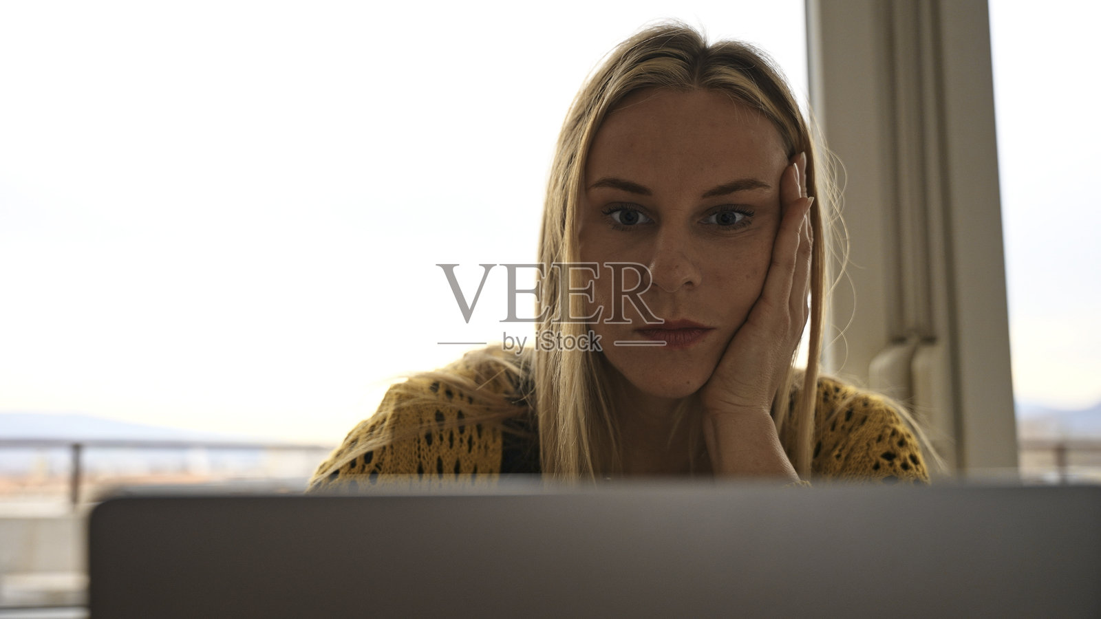 年轻女性担忧地看着笔记本电脑屏幕照片摄影图片