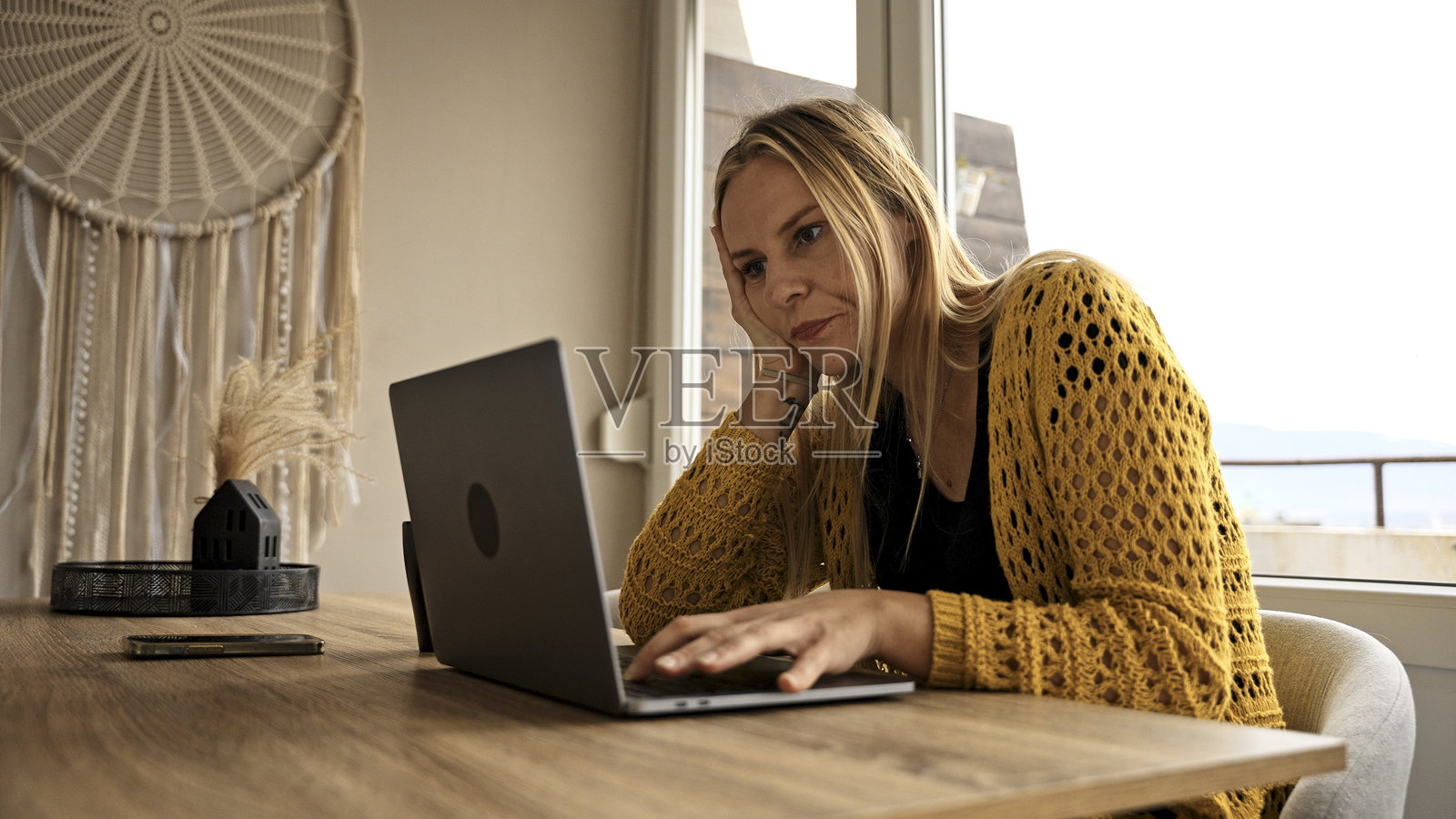 无聊的年轻女性在家工作，正盯着笔记本电脑。照片摄影图片