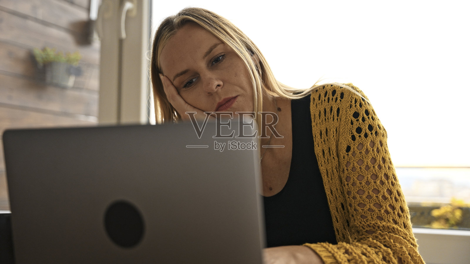 疲惫的女商人在家工作，感到无聊，盯着笔记本电脑。照片摄影图片