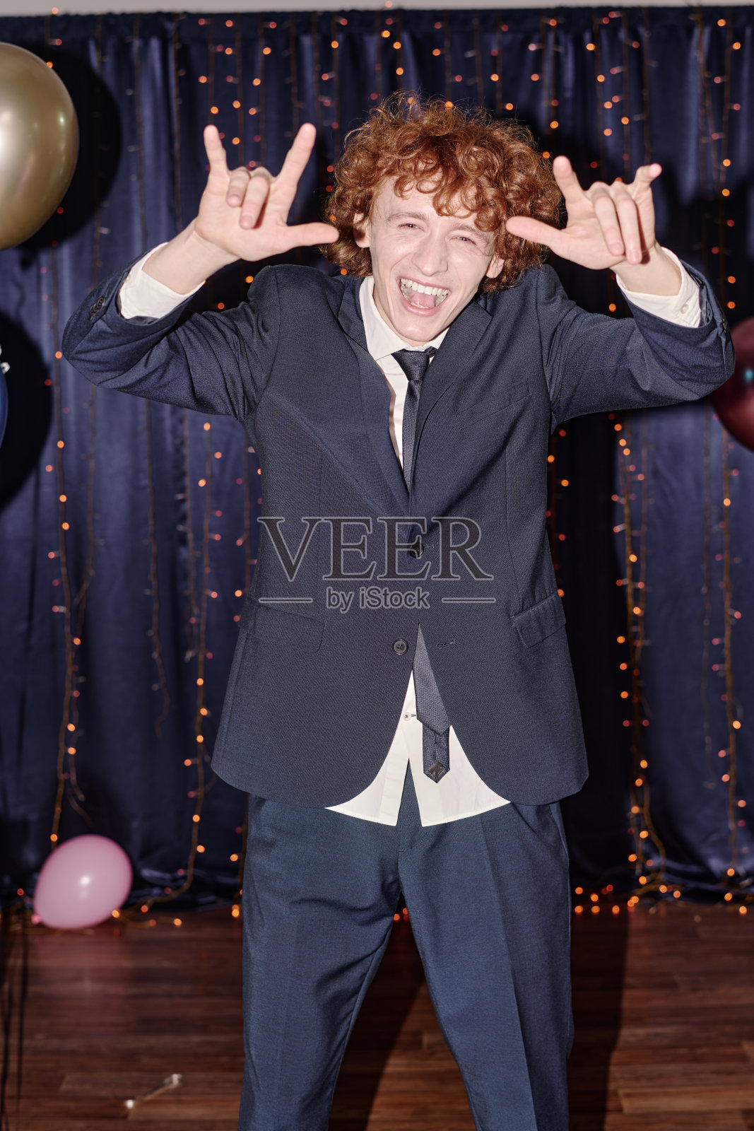 青少年男孩在舞会庆祝活动中微笑并做手势的肖像照片摄影图片