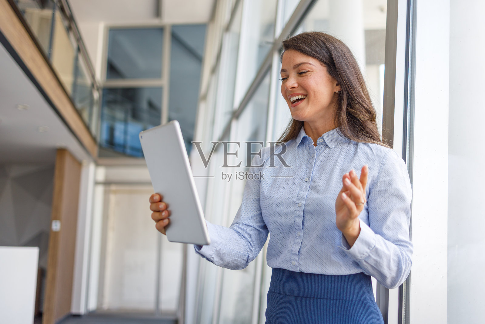 在现代办公大楼中，女商人正在通过平板电脑进行视频通话照片摄影图片