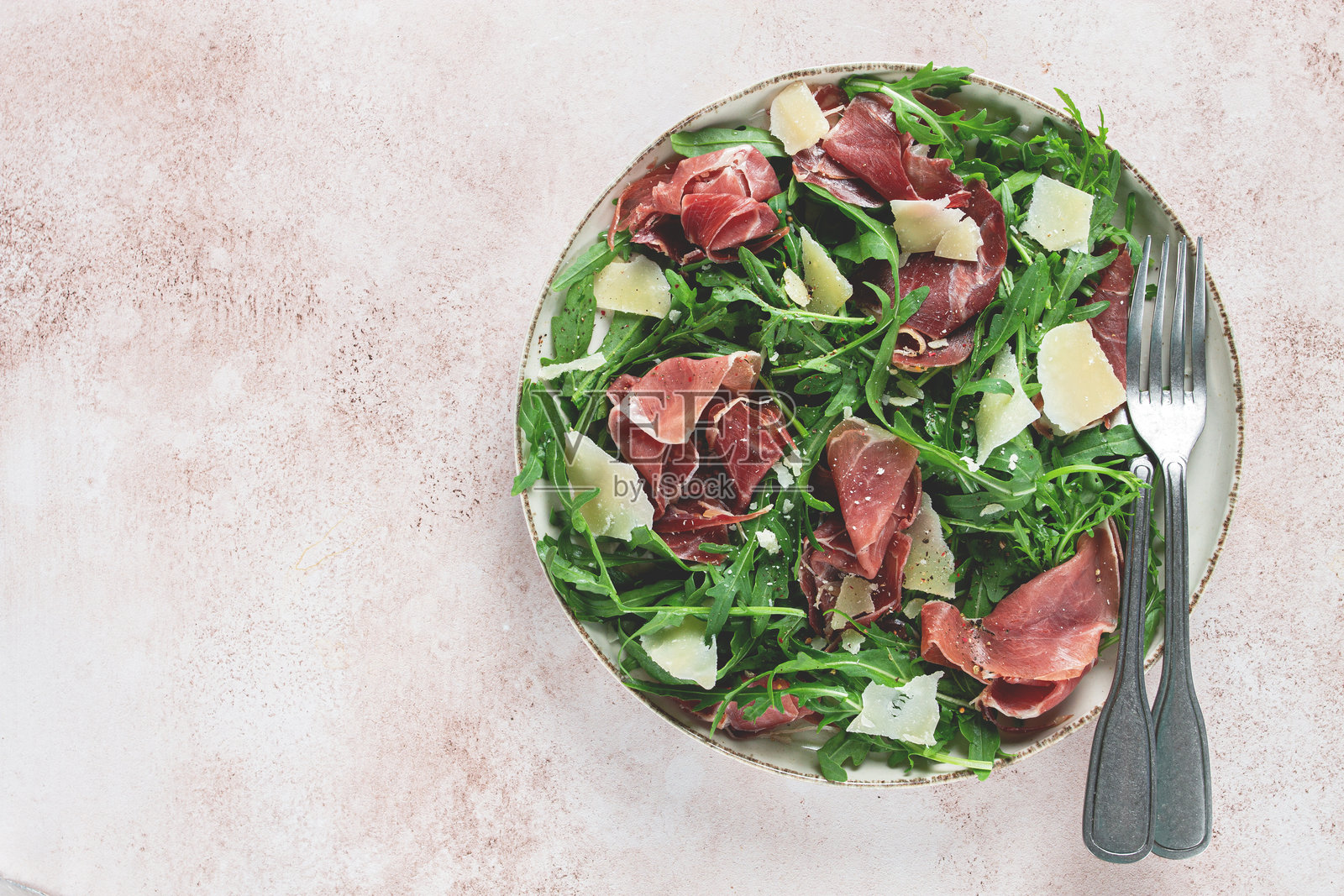 新鲜的芝麻菜沙拉，配有意大利熏火腿和磨碎的帕尔马干酪，摆放在盘子上，自制，无人。照片摄影图片