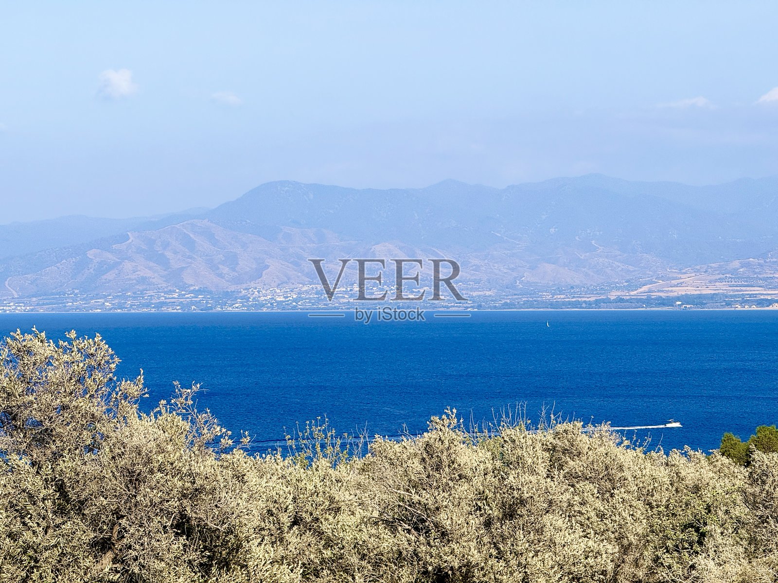 公共海滩，夏季，阳光明媚的天气。风景如画的海滩，海浪拍打着沙滩。海浪冲击着岩石。塞浦路斯岛，遮阳伞，游客船，地中海。照片摄影图片