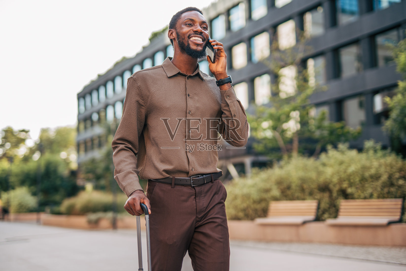 微笑的商人提着手提箱走路并打电话照片摄影图片