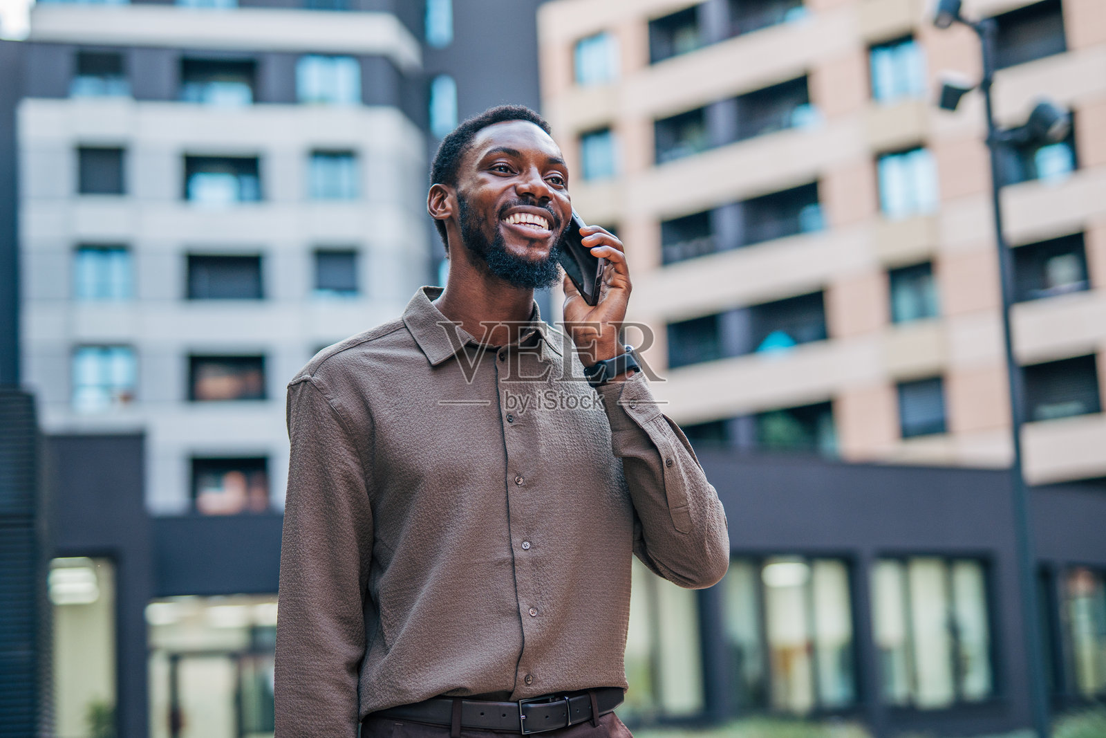 年轻的商人在城市中微笑着打电话照片摄影图片