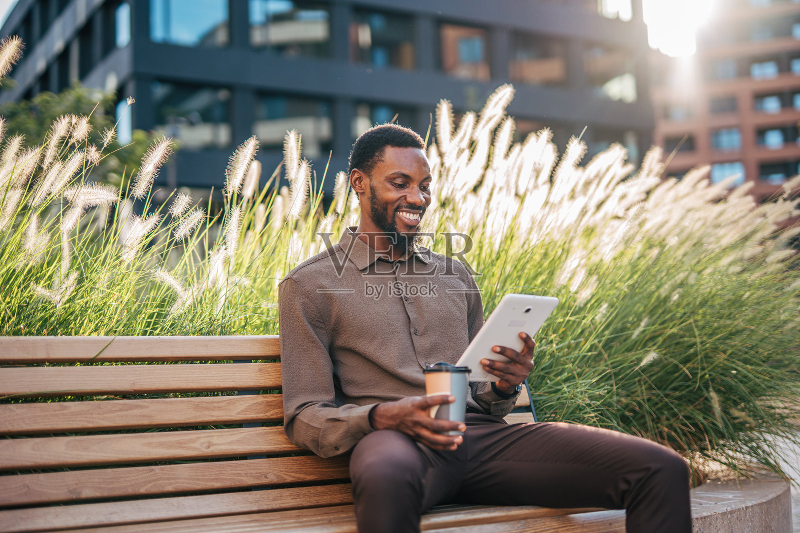 微笑的商人在户外使用平板电脑并喝咖啡照片摄影图片
