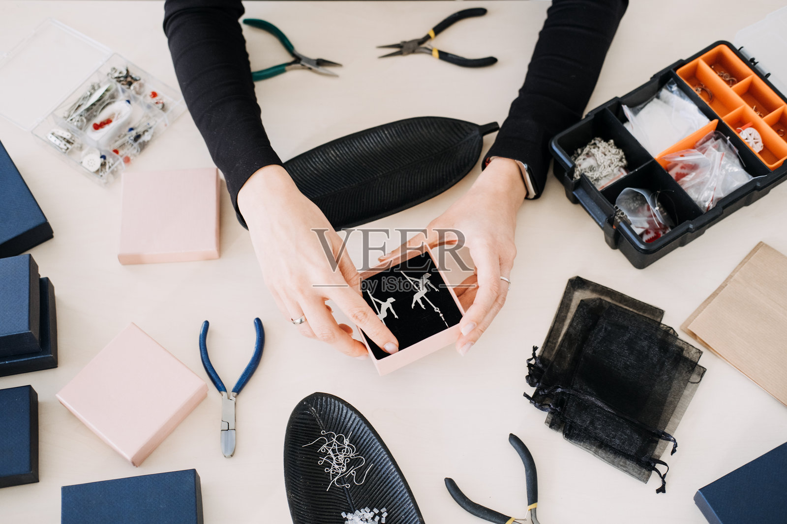 手中展示着装在礼品盒里的手工耳环。展示可持续的珠宝设计、环保包装和道德工艺。照片摄影图片