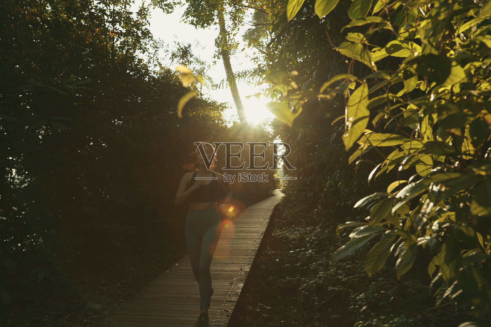 一位中国女性在水边的自然小道木栈道上跑步照片摄影图片