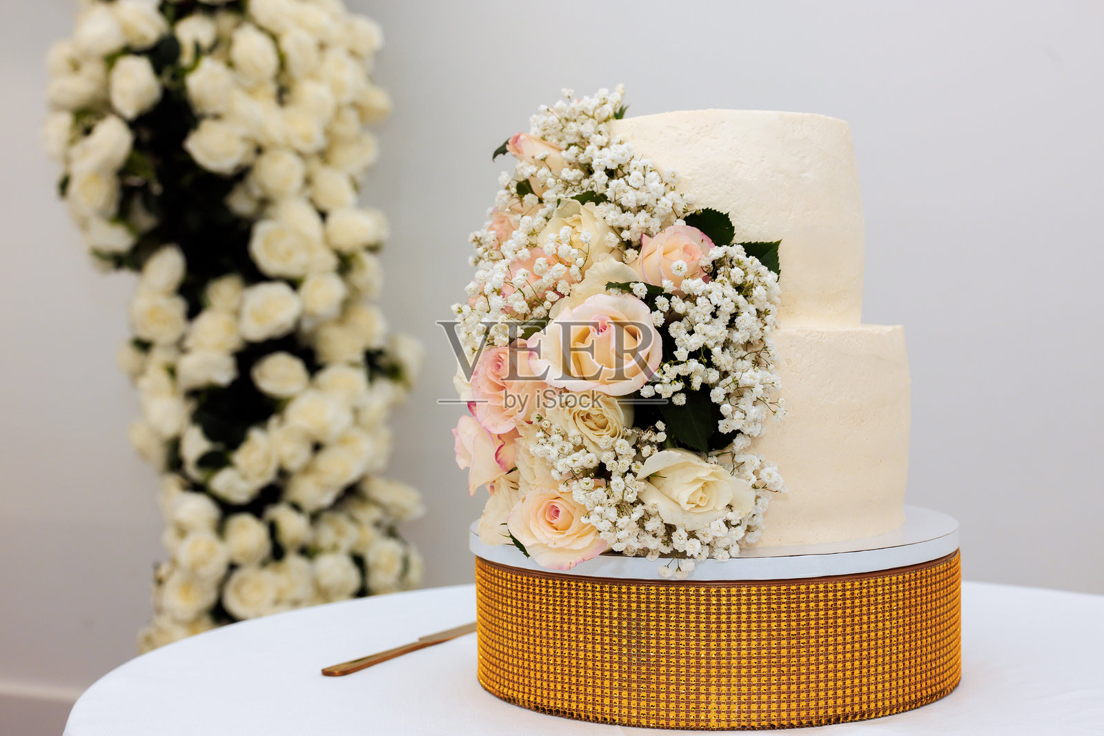 优雅的白色婚礼蛋糕，装饰着玫瑰和满天星，适合庆祝的精美场地照片摄影图片