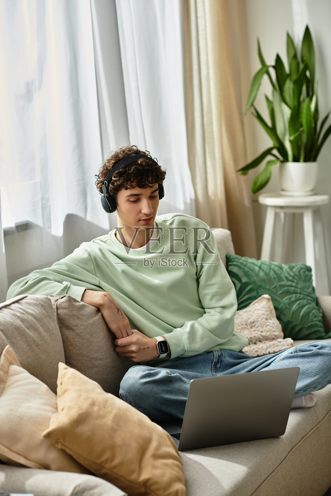 一个专注的年轻男子，卷发，在阳光明媚的下午在舒适的家庭办公室工作照片摄影图片