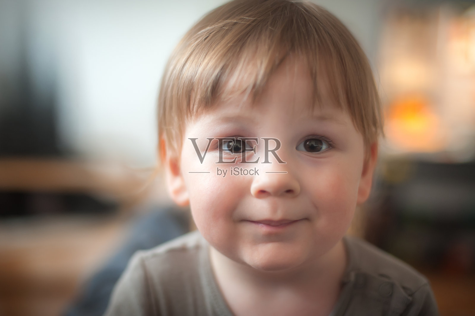 一个快乐的棕色短发小男孩在舒适的午后，在柔和的光线下微笑照片摄影图片