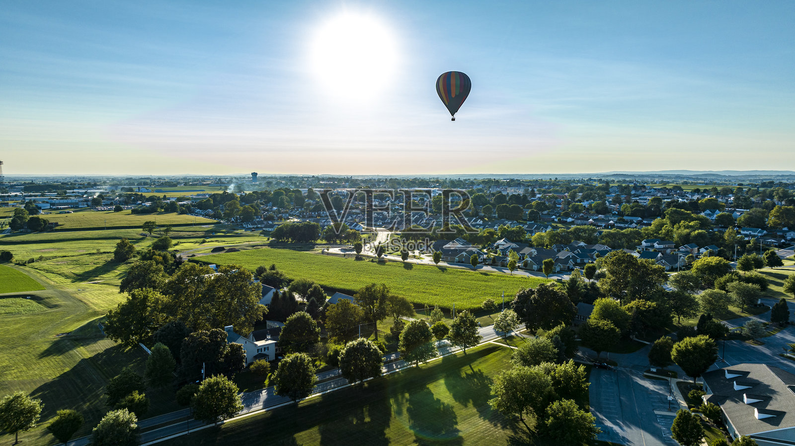 从空中俯瞰漂浮在乡村社区上空的条纹热气球照片摄影图片