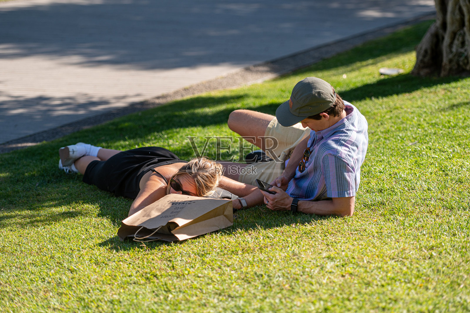 一对情侣在阳光明媚的下午享受躺在草地上的悠闲时光。照片摄影图片