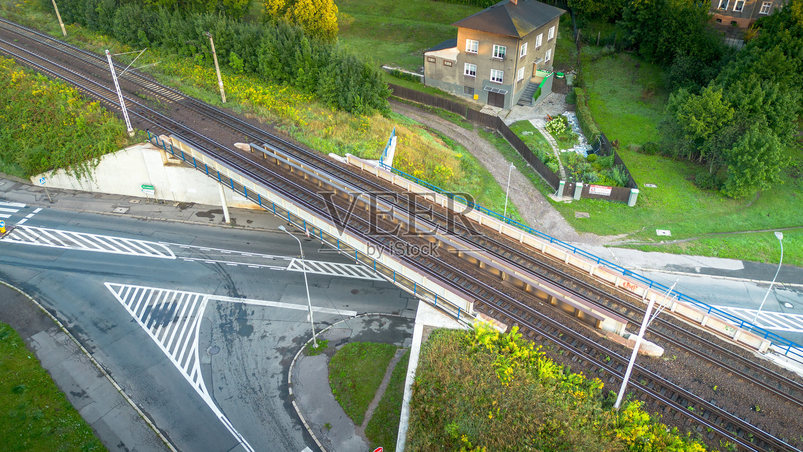 下午鸟瞰图，住宅区附近的一个铁路道口被绿色植物包围照片摄影图片
