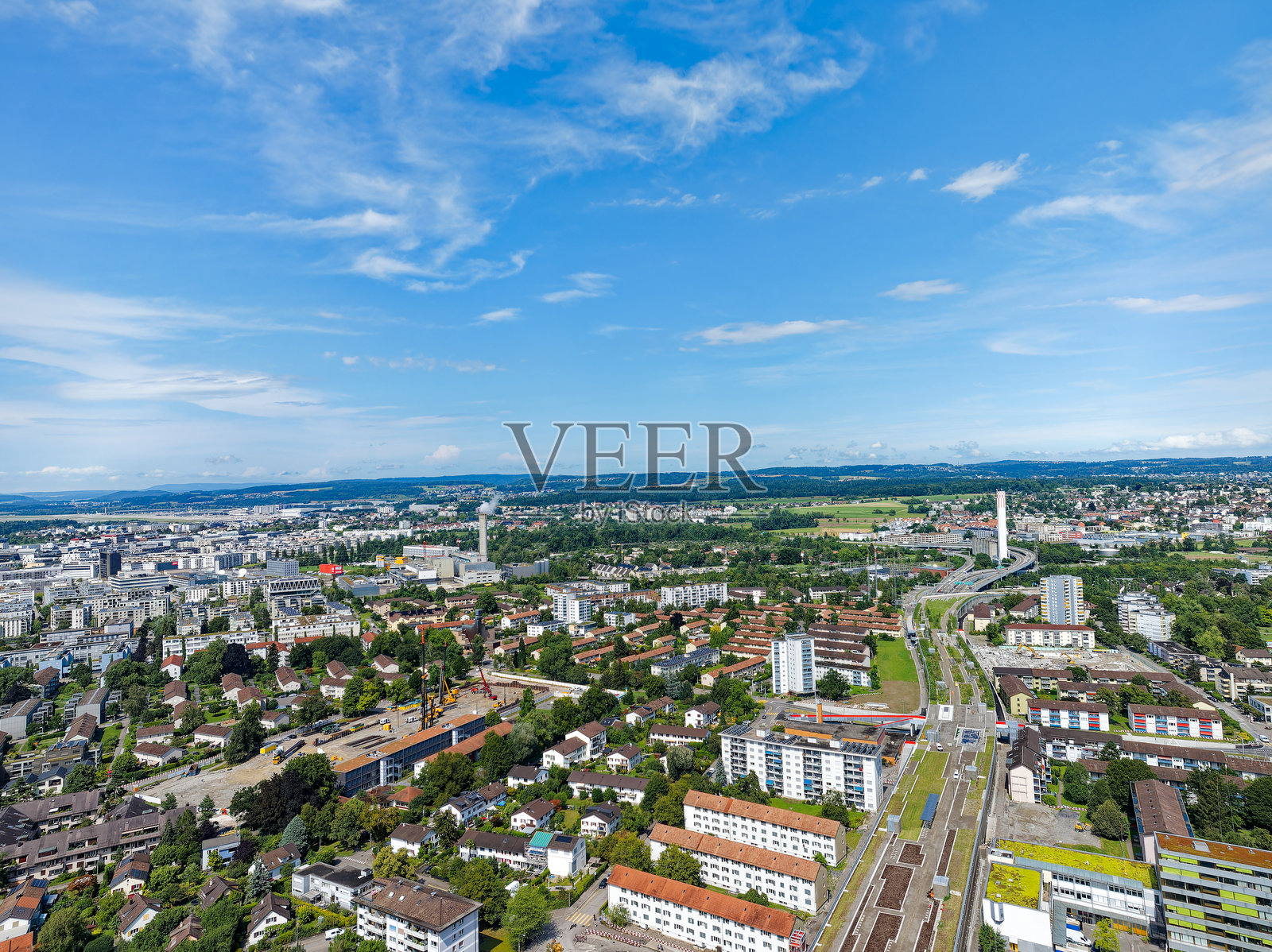 在一个阳光明媚的夏日午后，无人机从瑞士城市z<e:1>的角度观察城市景观和建筑工地。照片摄影图片