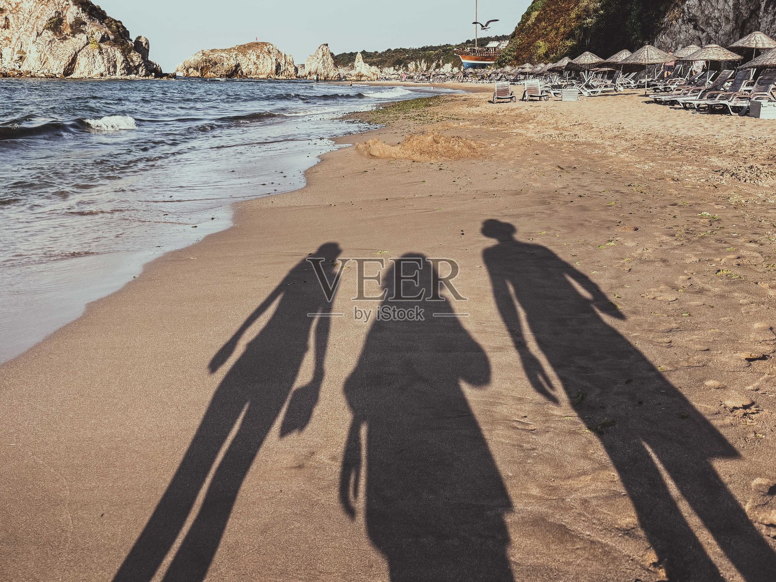 三个人在宁静的沙滩上散步的影子照片摄影图片