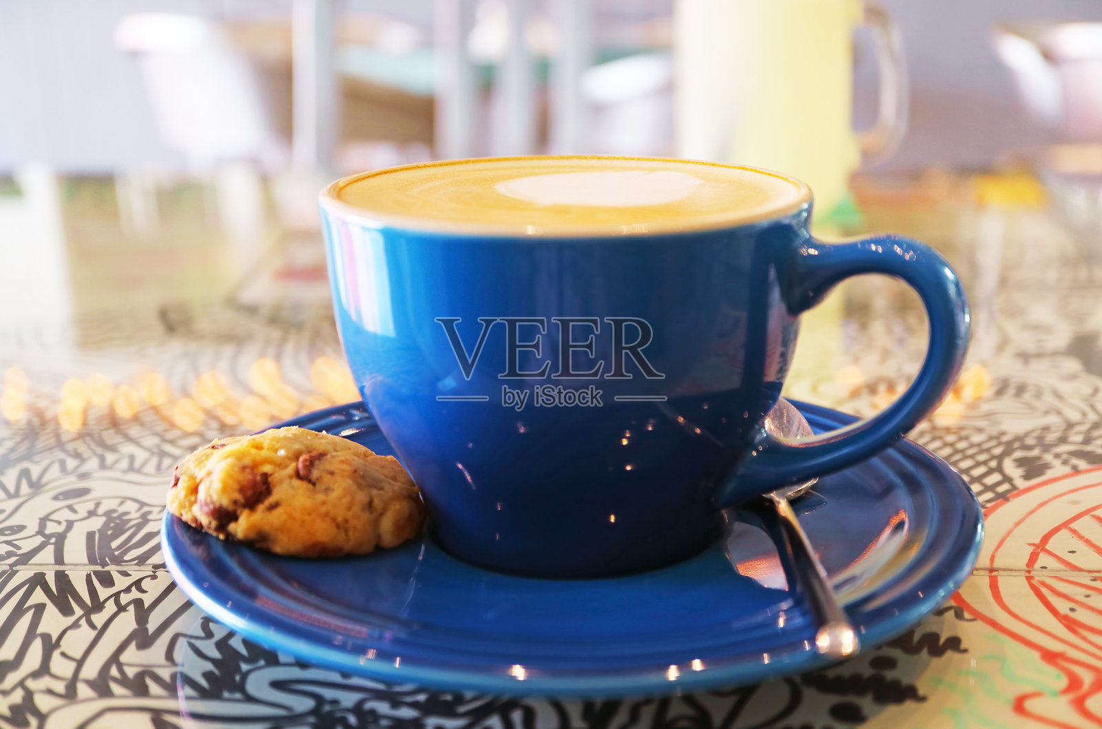 一杯卡布奇诺咖啡，桌上放着一块巧克力曲奇照片摄影图片