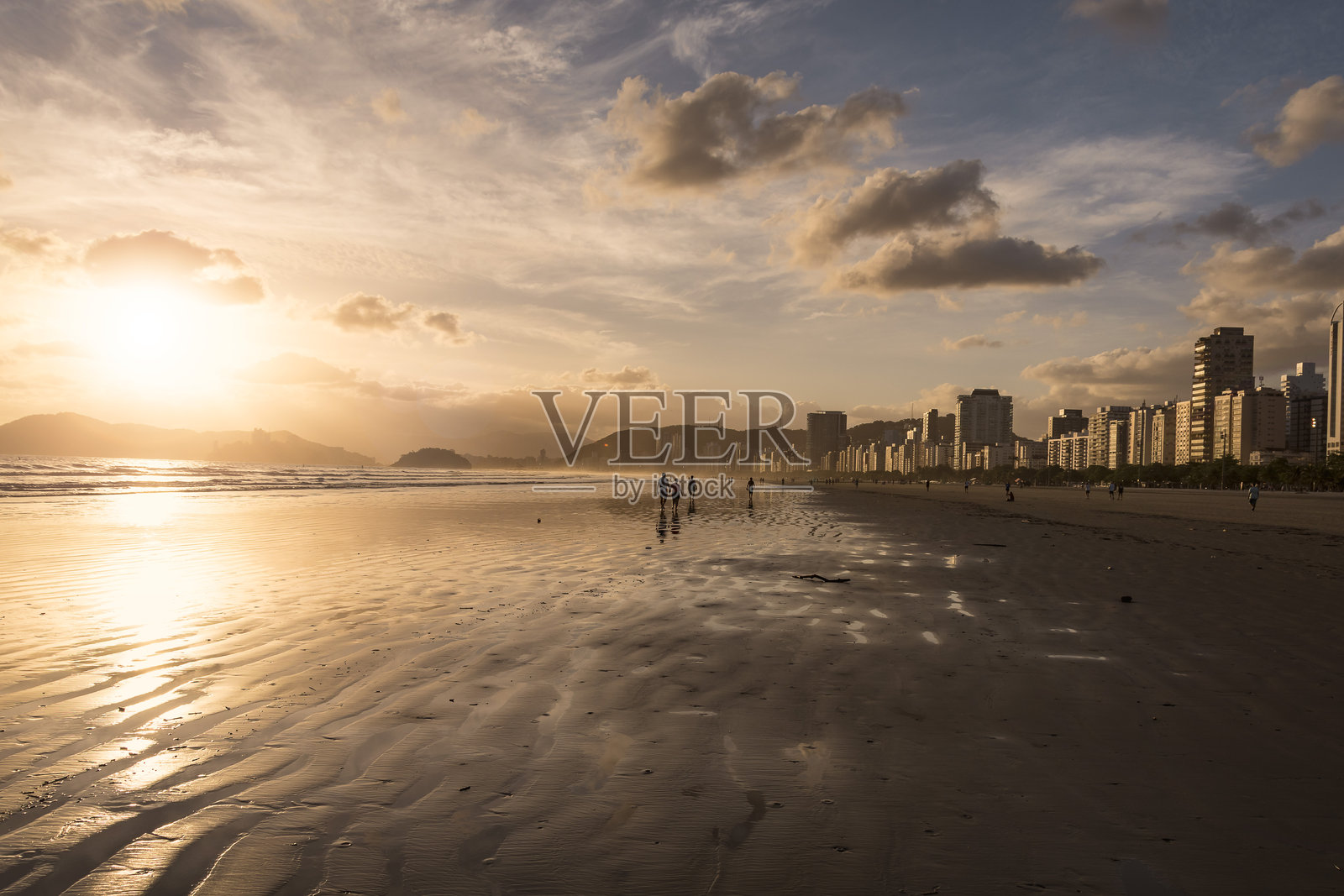 巴西桑托斯市。日落在桑托斯海滩与海滨建筑照亮阳光在蓝色的天空。照片摄影图片