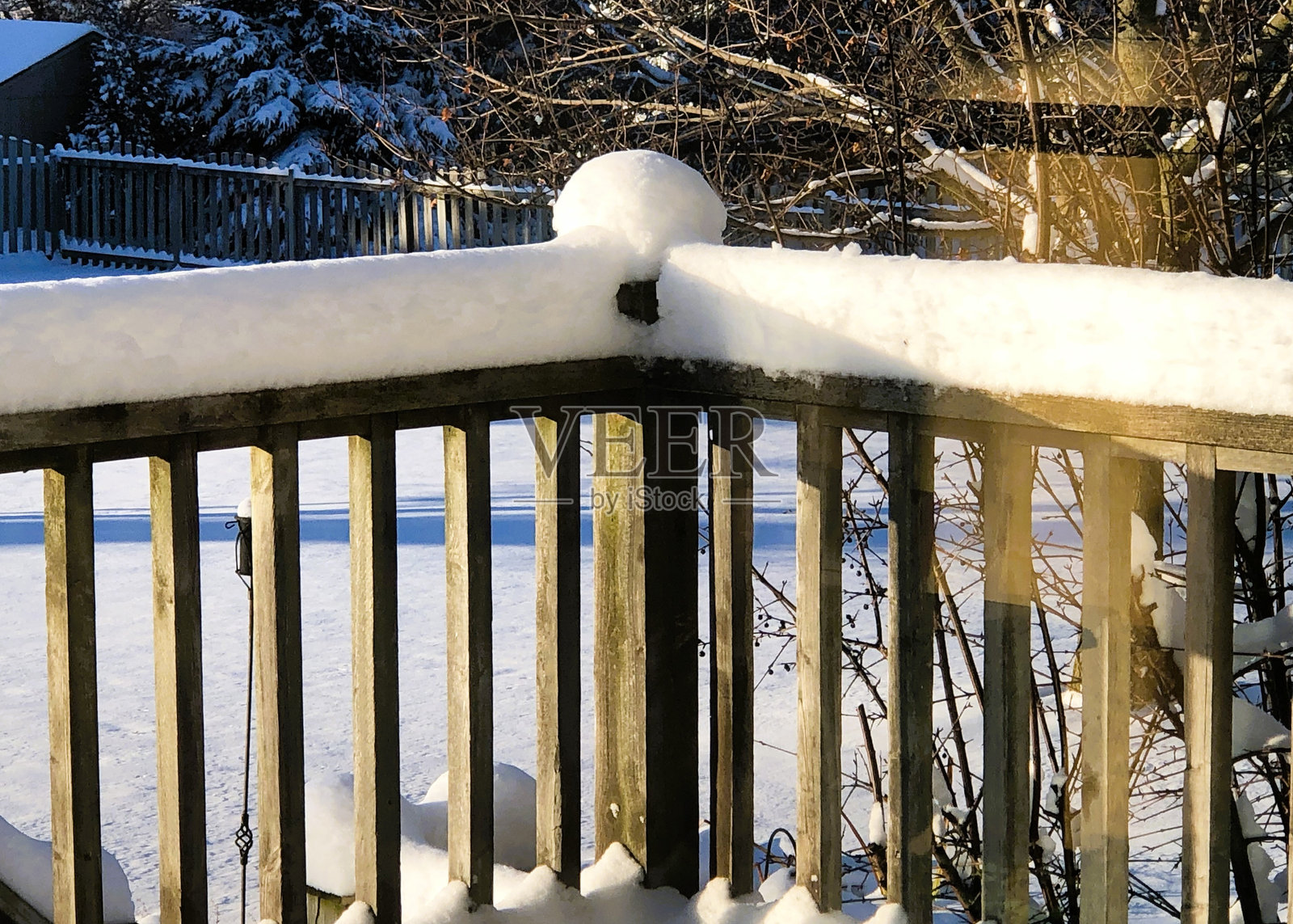 傍晚的阳光在新鲜的白雪上投下长长的影子。照片摄影图片