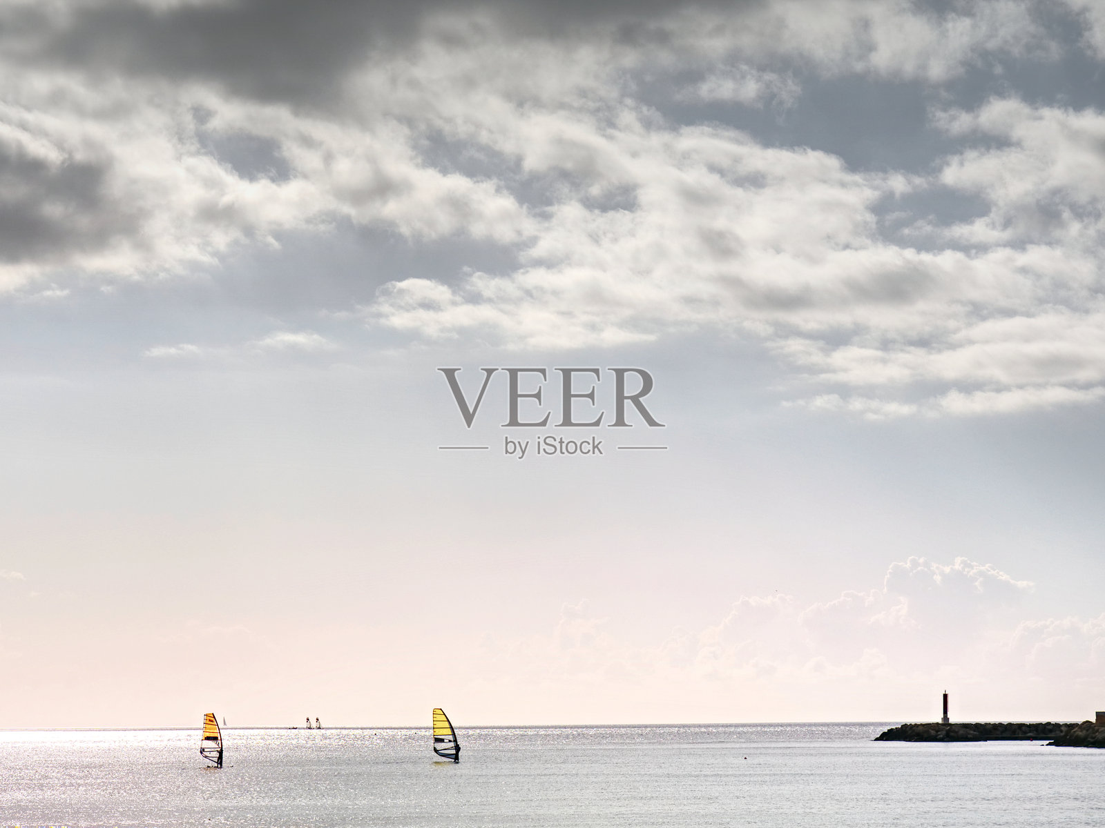 帆板上的男人。和风吹，下午的太阳在海浪中闪闪发光照片摄影图片